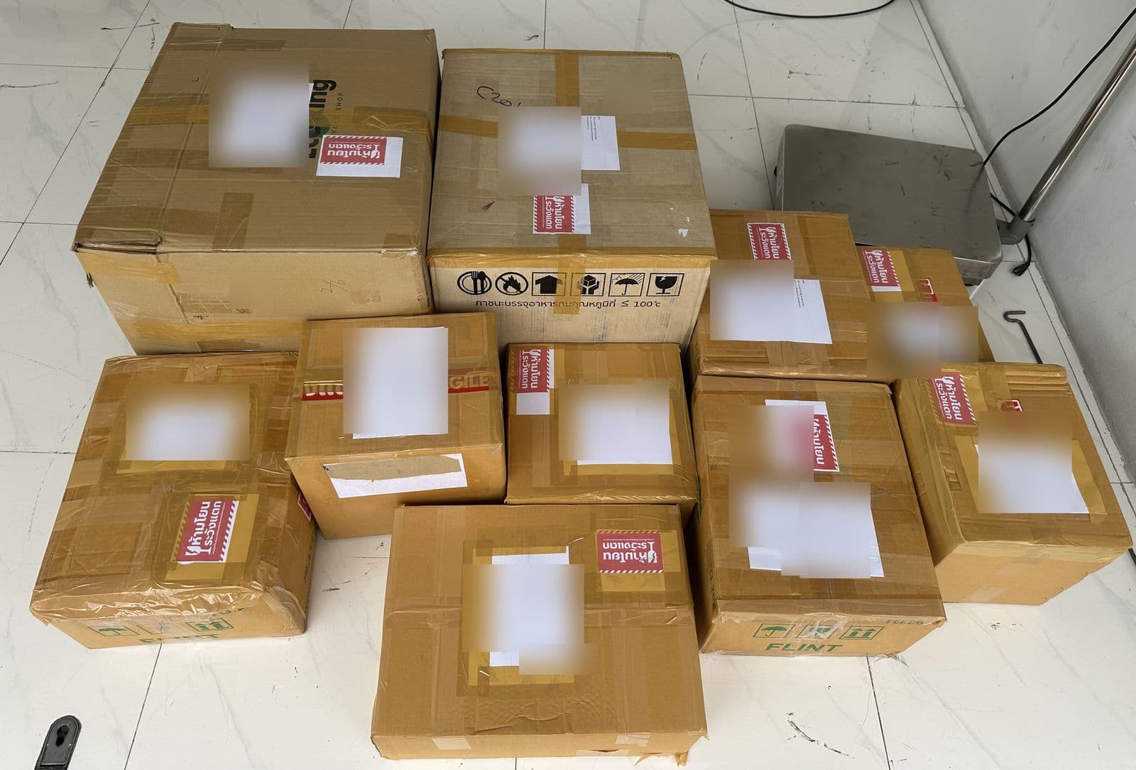 An order packed into ten numbered cartons, marked fragile and weighed on the warehouse scale before courier handover. Shipping labels blurred.